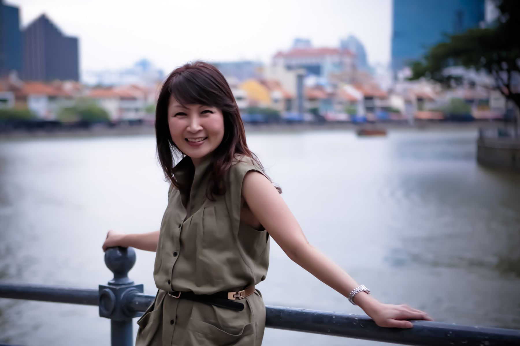 Eve Lyn Phang standing by the railings of the Singapore River, with the shophouses of Boat Quay behind her